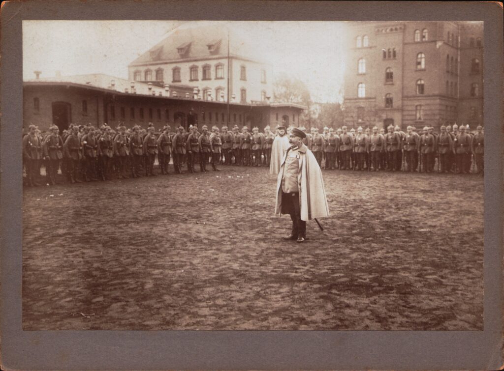 Appell an der Kaserne am Pferdemarkt, 1914, © Stadtmuseum Oldenburg Appell an der Kaserne am Pferdemarkt 1914 mit Soldaten in Uniform und einem Offizier in Mantel, © Stadtmuseum Oldenburg