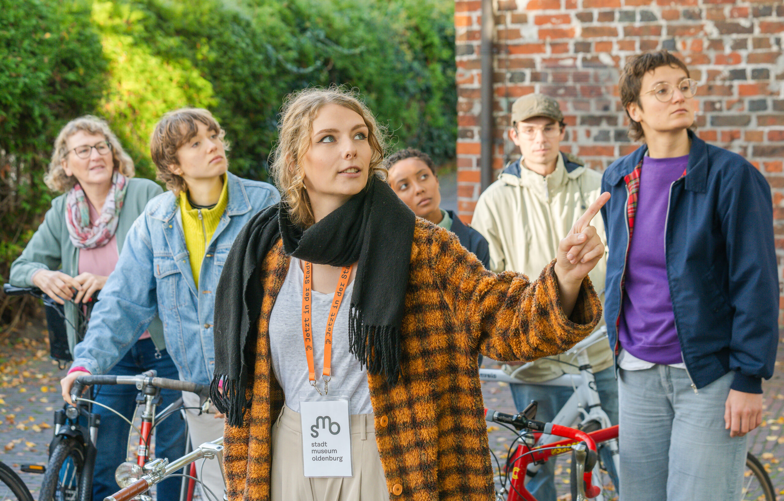 Eine Exkursions-Gruppe steht vor der St. Gertruden Kirche und schaut sich diese von Außen interessiert an, © Studio 3x3