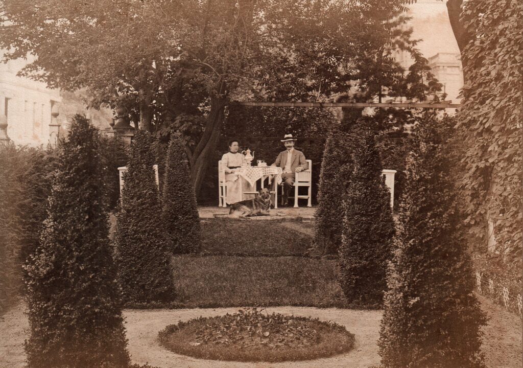 Ba 2735 Theo Francksen Helene Knoche Museumsgarten 1912 Bearbeitet Historische Fotografie von Theodor Francksen und Helene Knoche an einem Tisch im Garten sitzend, mit Schäferhund, © Stadtmuseum Oldenburg