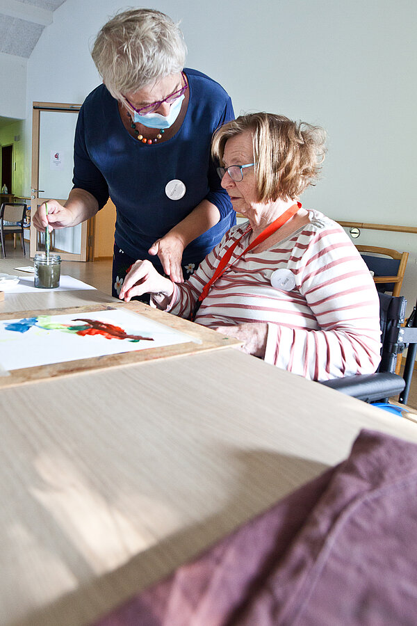 Eine Person wird angeleitet ein Bild mit Tuschfarben zu malen, © Gerlinde Domininghaus Eine Person wird angeleitet ein Bild mit Tuschfarben zu malen, © Gerlinde Domininghaus