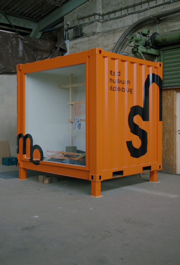 Orangener Container des Stadtmuseums mit Fensterfront und Aufdruck des SMO-Logos, © Stadtmuseum Oldenburg
