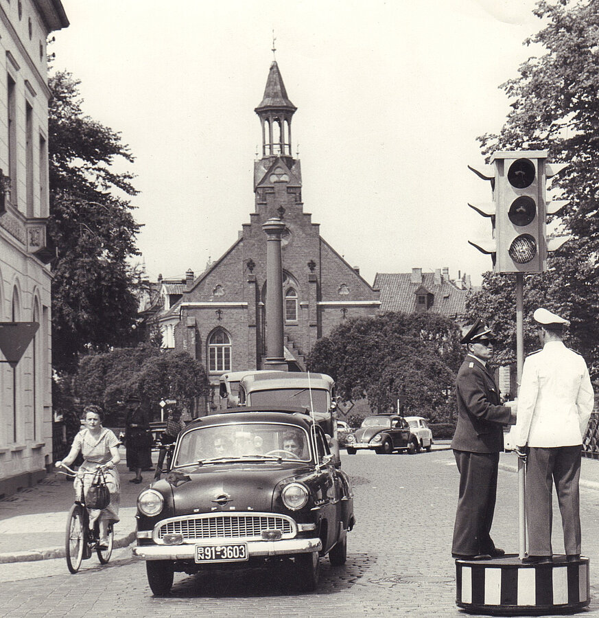 Schwarz weiß Bild mit Blick auf den Friedenssäule ohne Spitze, dahinter die Friedenskirche, im Vordergrund Verkehr, © Stadtmuseum Oldenburg/Günter Nordhausen