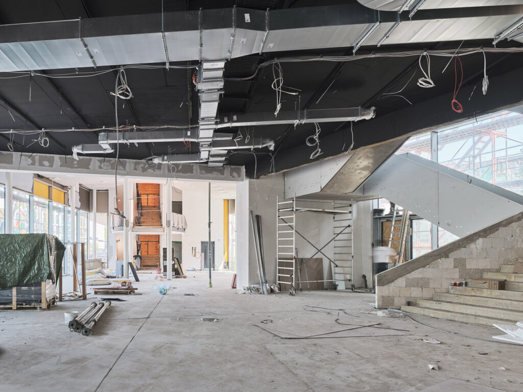 Innenraum einer Baustelle mit freiliegenden Kabeln, Treppe aus Beton und unvollständigen Wänden, © Caspar Sessler