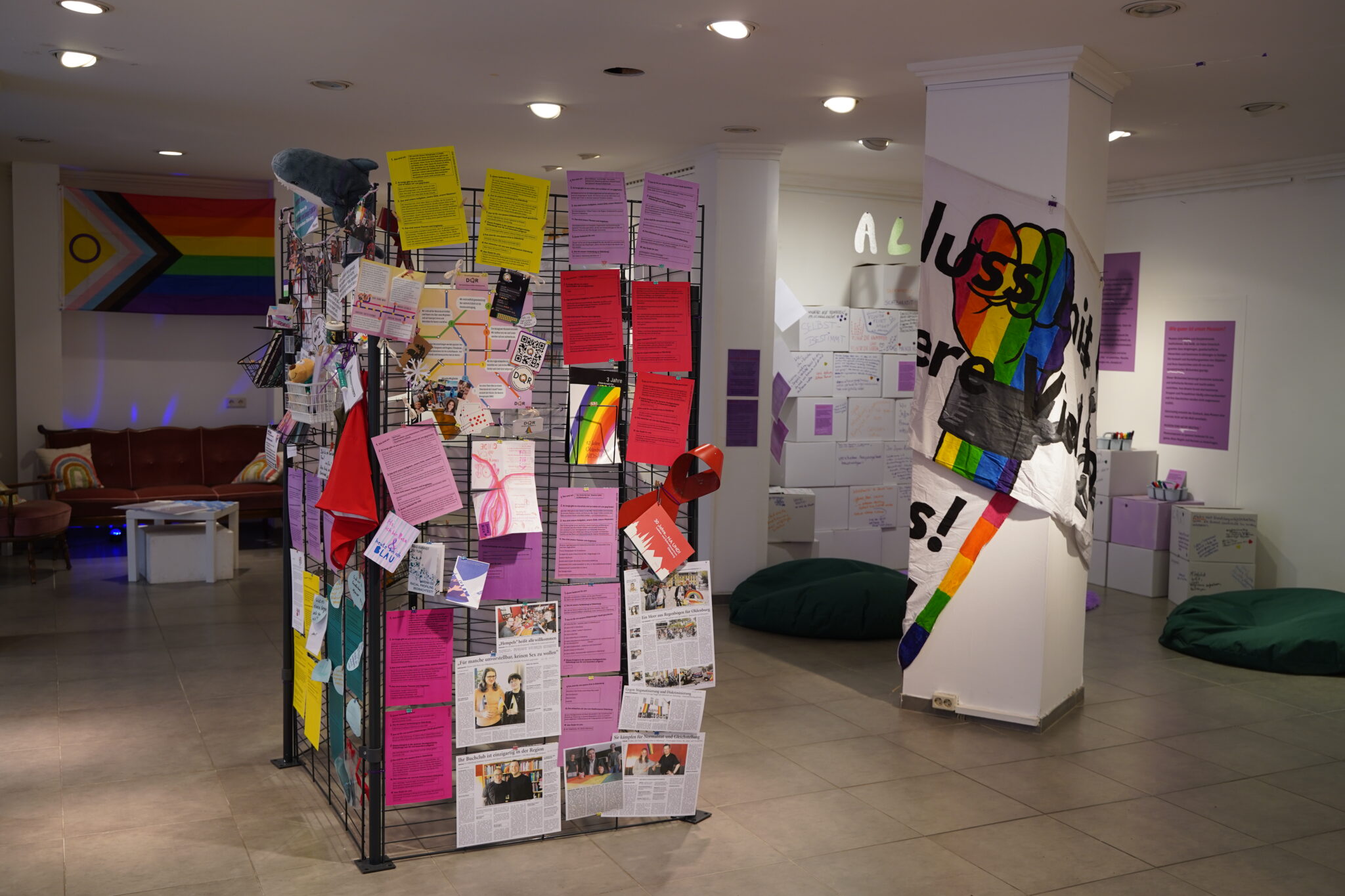Ausstellungsraum mit Infotafeln zu queeren Themen, Regenbogenflagge und Sitzbereich, © Stadtmuseum Oldenburg