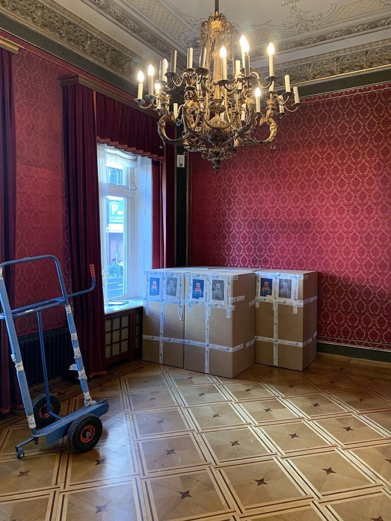 Historischer roter Salon mit Kronleuchter, gepackten Kartons und blauer Sackkarre, © Stadtmuseum Oldenburg