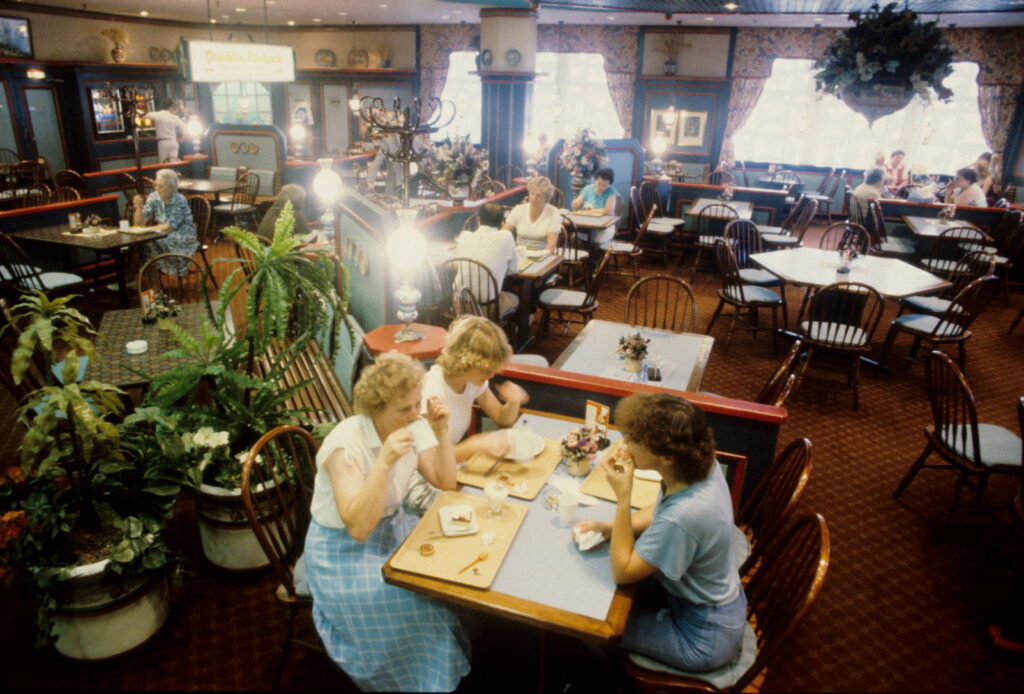 Personen sitzen in einem Restaurant an Tischen, dekoriert ist der Raum mit Pflanzen und hellen Lichtern, © Stadtmuseum Oldenburg