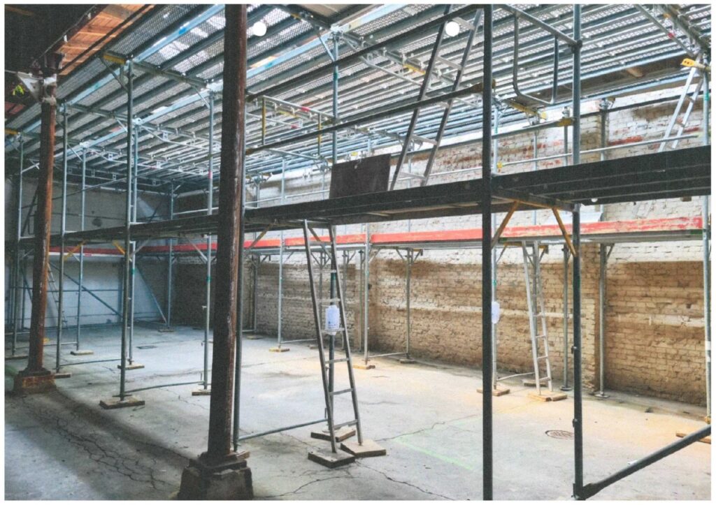 Innenansicht der Baustelle in der alten Maschinenhalle, 2024, © Katharina Semling Halle mit Baugerüsten, Leitern führen nach oben, © Katharina Semling