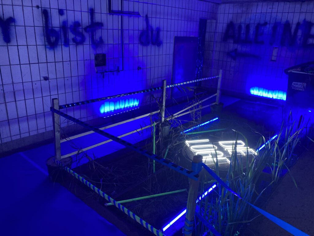 Geflieste Wand mit aufgesprühter Schrift, in blauem Neonlicht