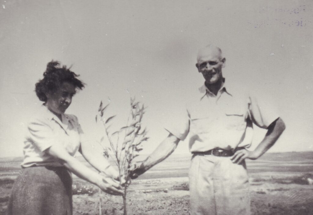 Zwei Personen stehen auf einem weiten Feld und halten einen kleinen Baum, © Stadtmuseum Oldenburg/Slg. Friederichsen