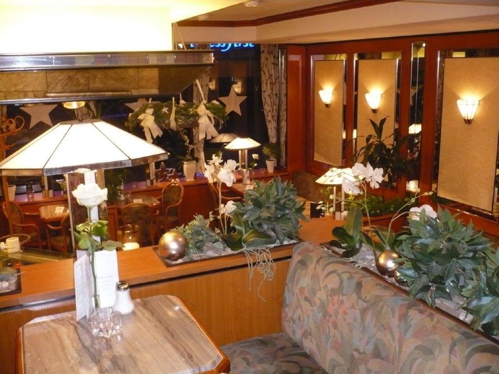 Abb. 4 Wiener Konditorei Innen Innenansicht eines Cafés mit einer Sitzbank und Tisch umgeben von Grünpflanzen und heller Beleuchtung, © Hans Janßen