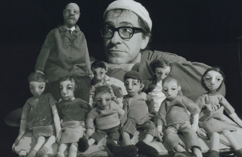 Aufgereihte Puppen, dahinter der Kopf eines Mannes mit Brille und Mütze, © Stadtmuseum Oldenburg