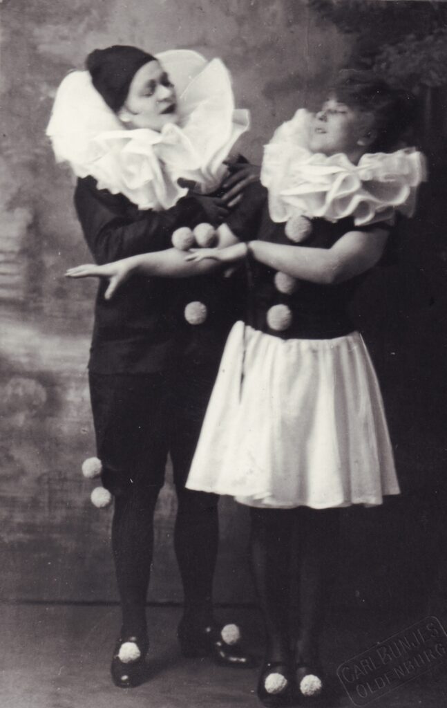 Zwei Frauen in Kostümen mit großen Halskrausen und weißen Bommeln an schwarzer Kleidung, © Stadtmuseum Oldenburg/Slg. Friederichsen