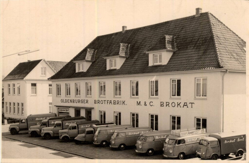 Ein weißes mehrstöckiges Gebäude mit der Aufschrift "Oldenburger Brotfabrik", davor Bullis und Lastwagen, © Stadtmuseum Oldenburg