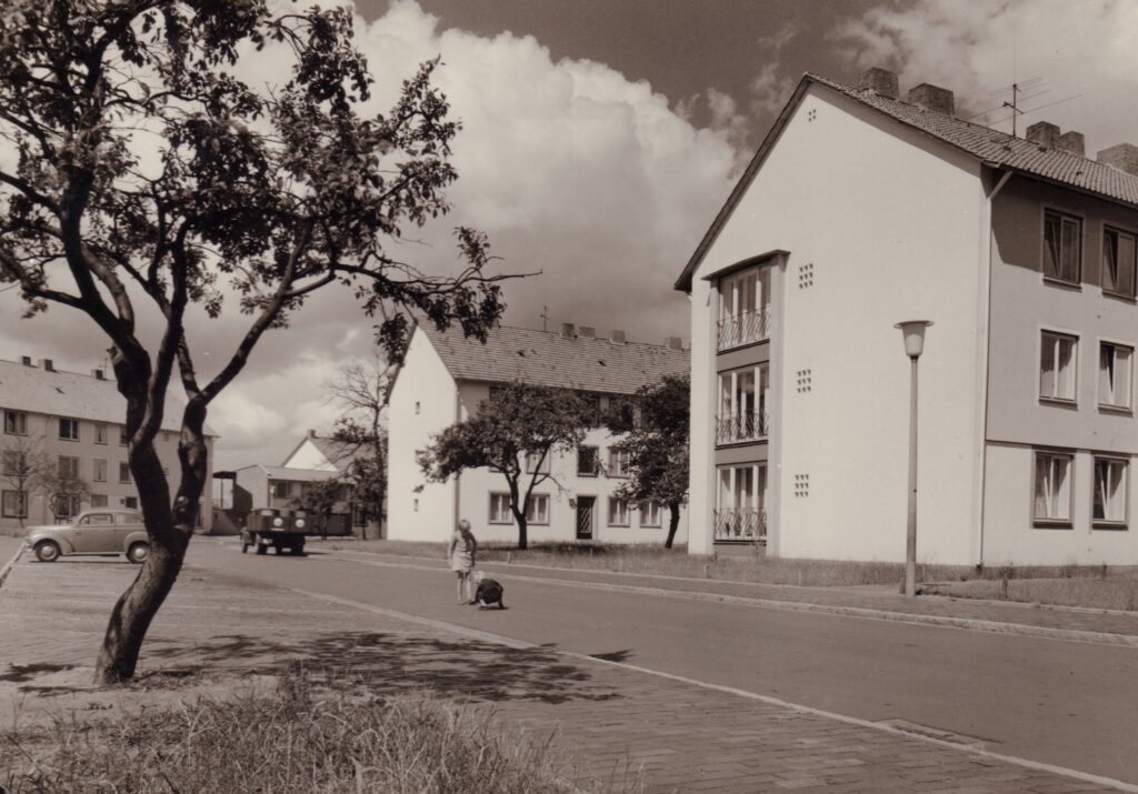 Mehrstöckige Gebäude an einer Straße, darauf Autos und eine Person, © Stadtmuseum Oldenburg