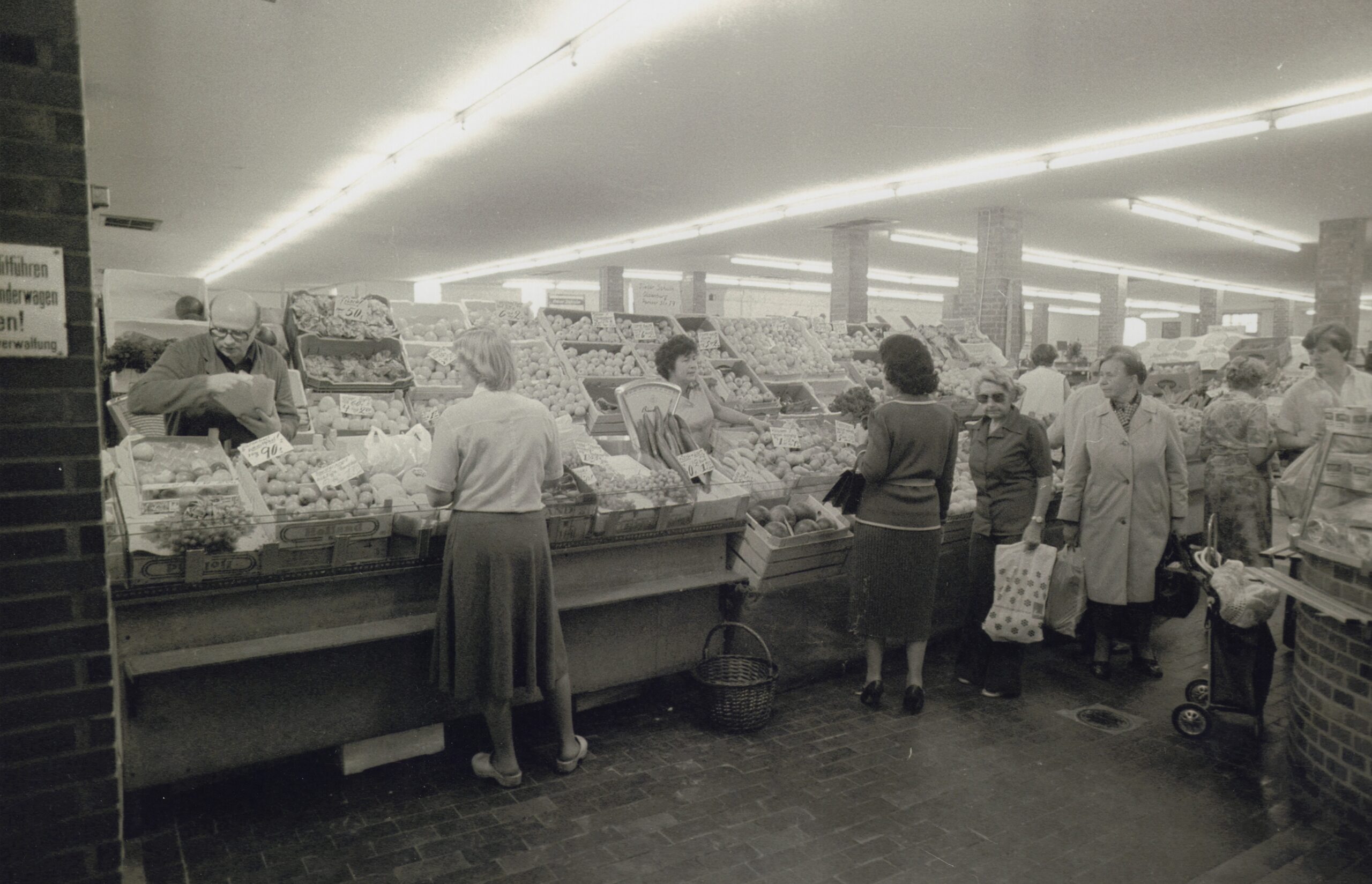Personen in einem Markt mit Obst- und Gemüse-Auslage, © Stadtmuseum Oldenburg/Peter Kreier