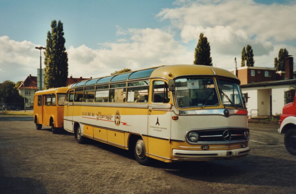 Zwei Fahrzeuge aus der Sammlung auf dem Gelände des Pekol-Museums im Jahr 2005, © Stadtmuseum Oldenburg/Prov. Friedrich Precht Alter gelbweißer Bus mit orangenem Gepäckanhänger auf einem Parkplatz, © Stadtmuseum Oldenburg/Prov. Friedrich Precht