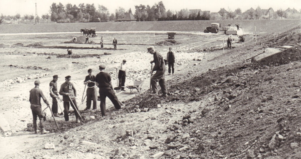 Marschwegstadion, aus Bauschutt errichtet durch von der Stadt beauftragte Notstandsarbeiter:innen, 1951, © Stadtmuseum Oldenburg/Günter Nordhausen Notstandsarbeiter errichten 1951 das Marschwegstadion in Oldenburg aus Bauschutt, mehrere Personen arbeiten mit Schaufeln und Schubkarren auf unebenem Gelände, © Stadtmuseum Oldenburg/Günter Nordhausen