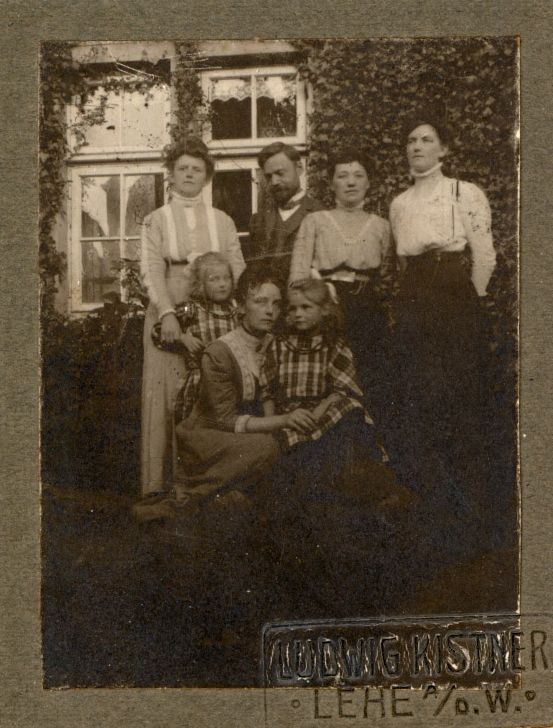 Familienfoto mit sieben Personen, ein Mann in Anzug, sechs Frauen in Kleidern, darunter zwei Kinder, stehen vor einem Efeu-bewachsenen Haus, © Stadtmuseum Oldenburg