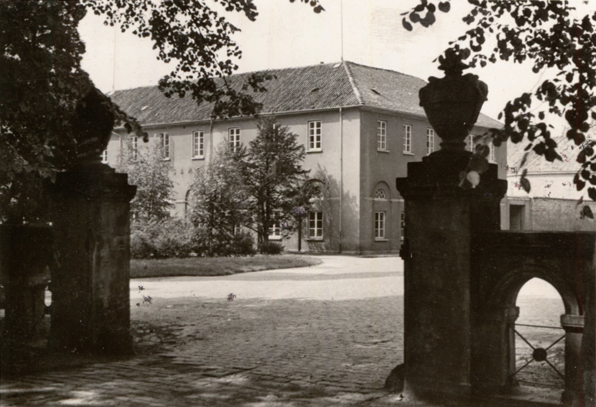 Ehemaliges Marstallgebäude Um 1950 Blick durch ein Tor auf einen gepflasterten Platz, dahinter ein Gebäude, © Stadtmuseum Oldenburg