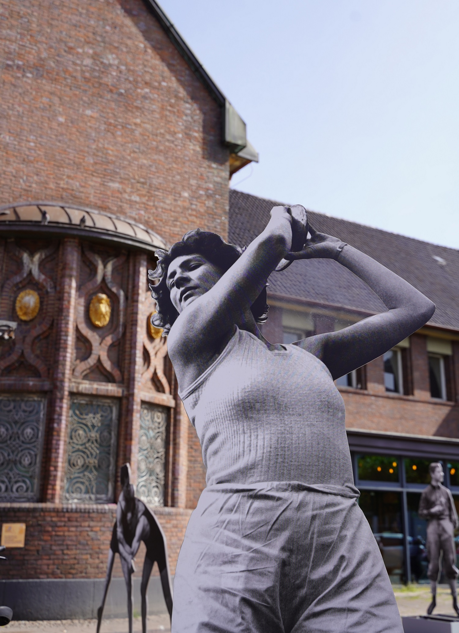 Skulptur von Leichtathletin Martha Jacob, © Stadtmuseum Oldenburg Skulptur der Leichtathletin Martha Jacob in sportlicher Pose mit verschränkten Armen vor einem Backsteingebäude, © Stadtmuseum Oldenburg