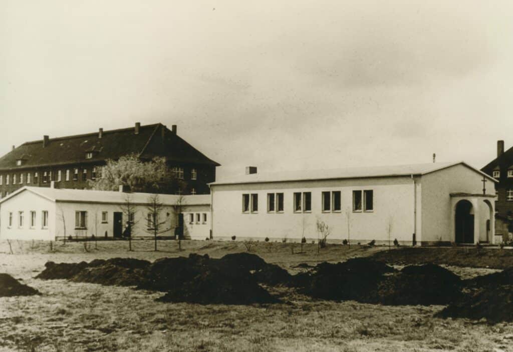 05 BA 32759 Notkirche Bei Hindenburg Kaserne 1953 Foto Josef Tenschert Die Notkirche bei der Städtischen Siedlung Kreyenbrück mit einem Kasernenblock im Hintergrund, 1953.