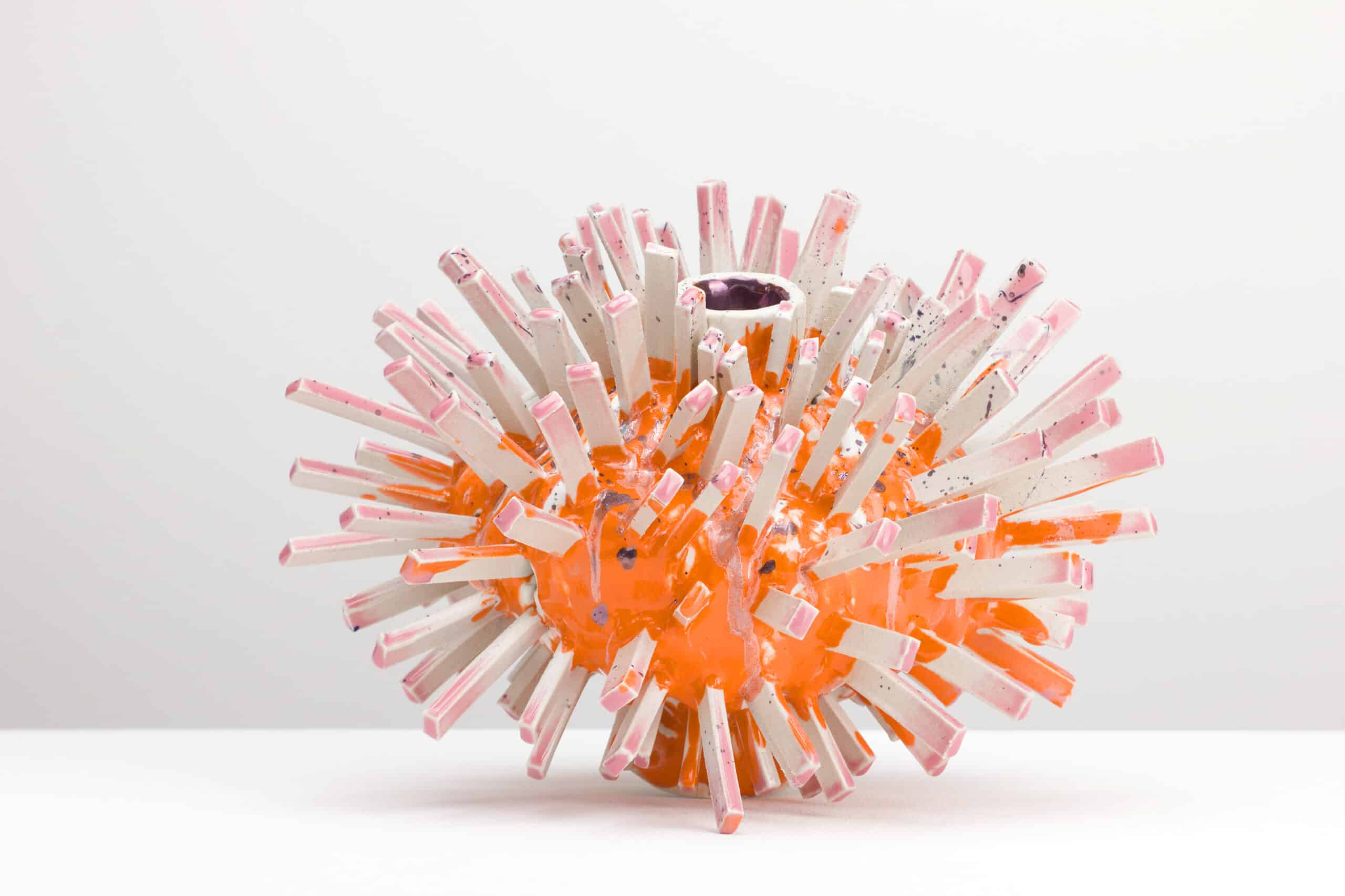 Lobster, Weißer Ton, Engobe, Glasur, 2026 © Maya Fenderl (2) Kunstobjekt aus weißem Ton mit oranger Glasur und zahlreichen länglichen Stäben, die radial aus der Mitte herausragen