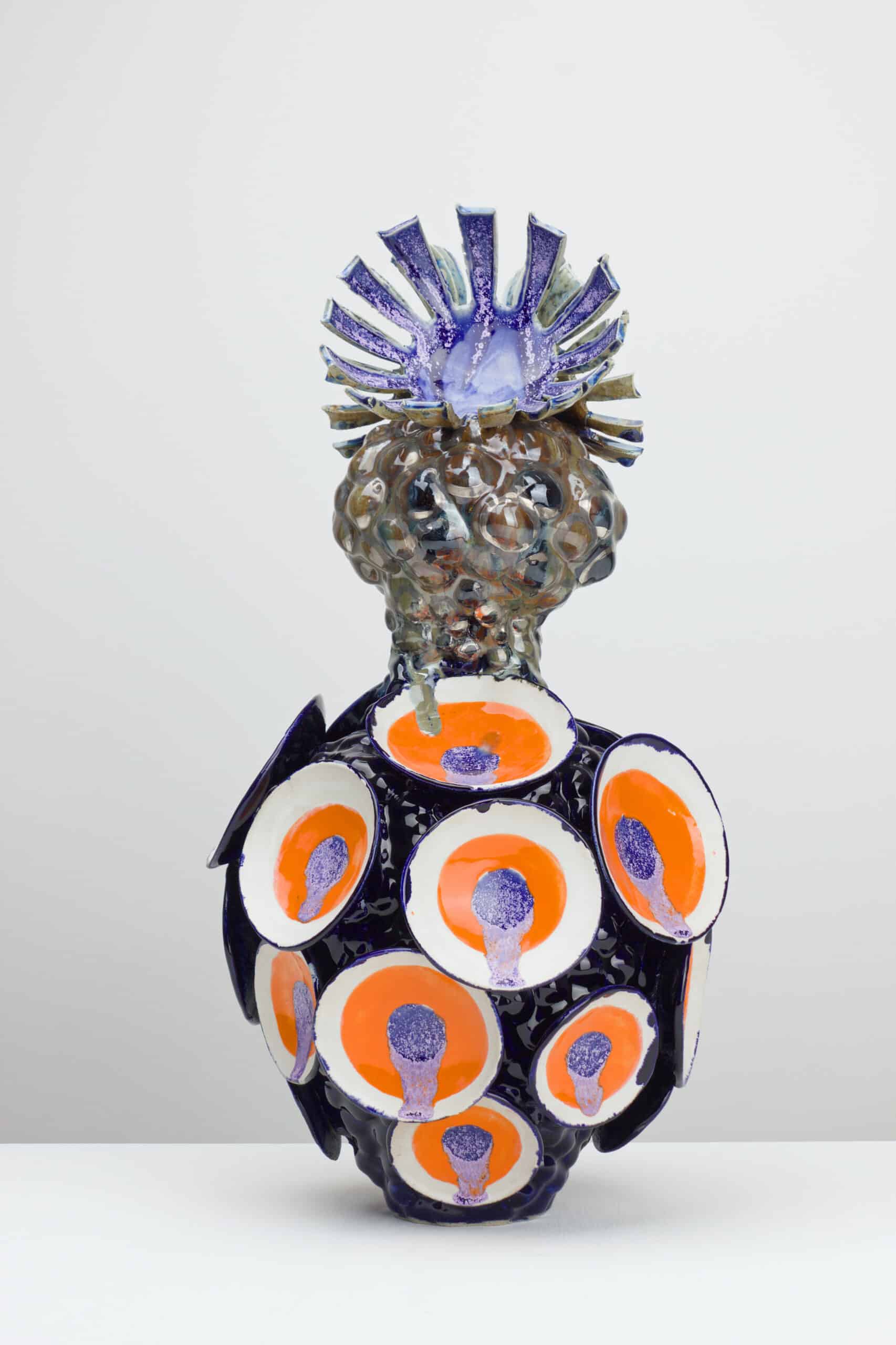 Maya Fenderl, Tutti Frutti, Weißer Ton, Engobe, Glasur, Lüster, 2026 © Maya Fenderl (2) Keramikvase mit kugelförmigem Körper, verziert mit orange-weißen Kreisen und einem skulpturalen, lilafarbenen Aufsatz in Form von Strahlen